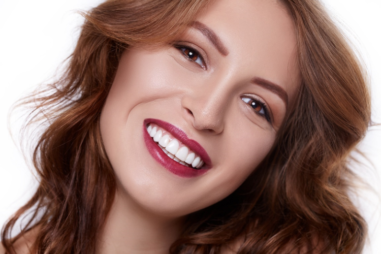 a beautiful woman with brown hair, red lips, brown eyes, and white teeth smiling.